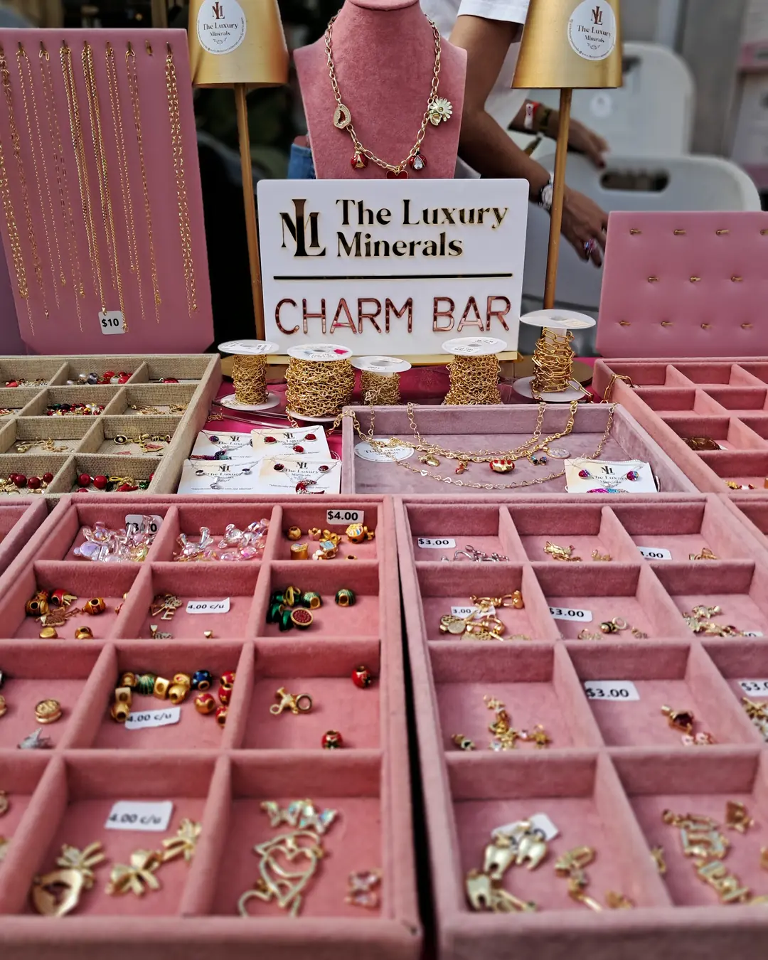 Charm Bar de The Luxury Minerals, foto 1: stand con bandejas de charms y dijes en oro 10K para armar pulseras