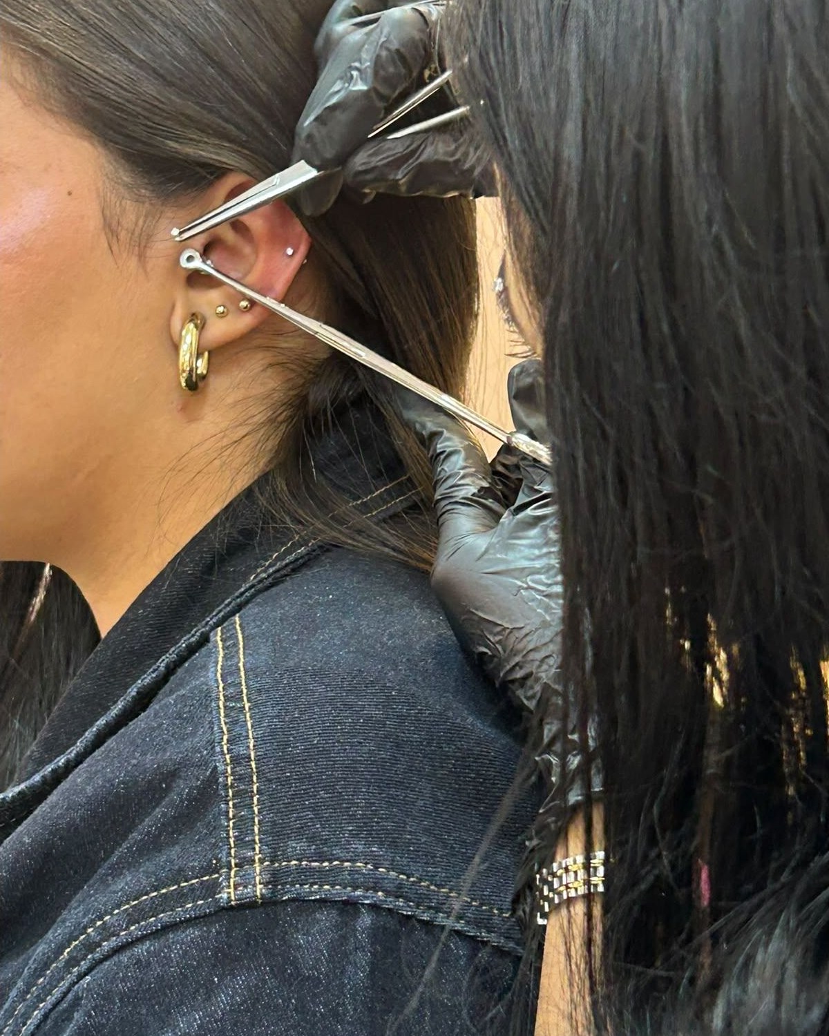 Aplicación profesional de piercing con material esterilizado frente a la vitrina de joyería
